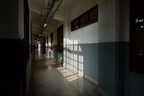 Free Sunlight casts shadows in an empty corridor of a modern building, creating a serene and contemplative atmosphere. Stock Photo