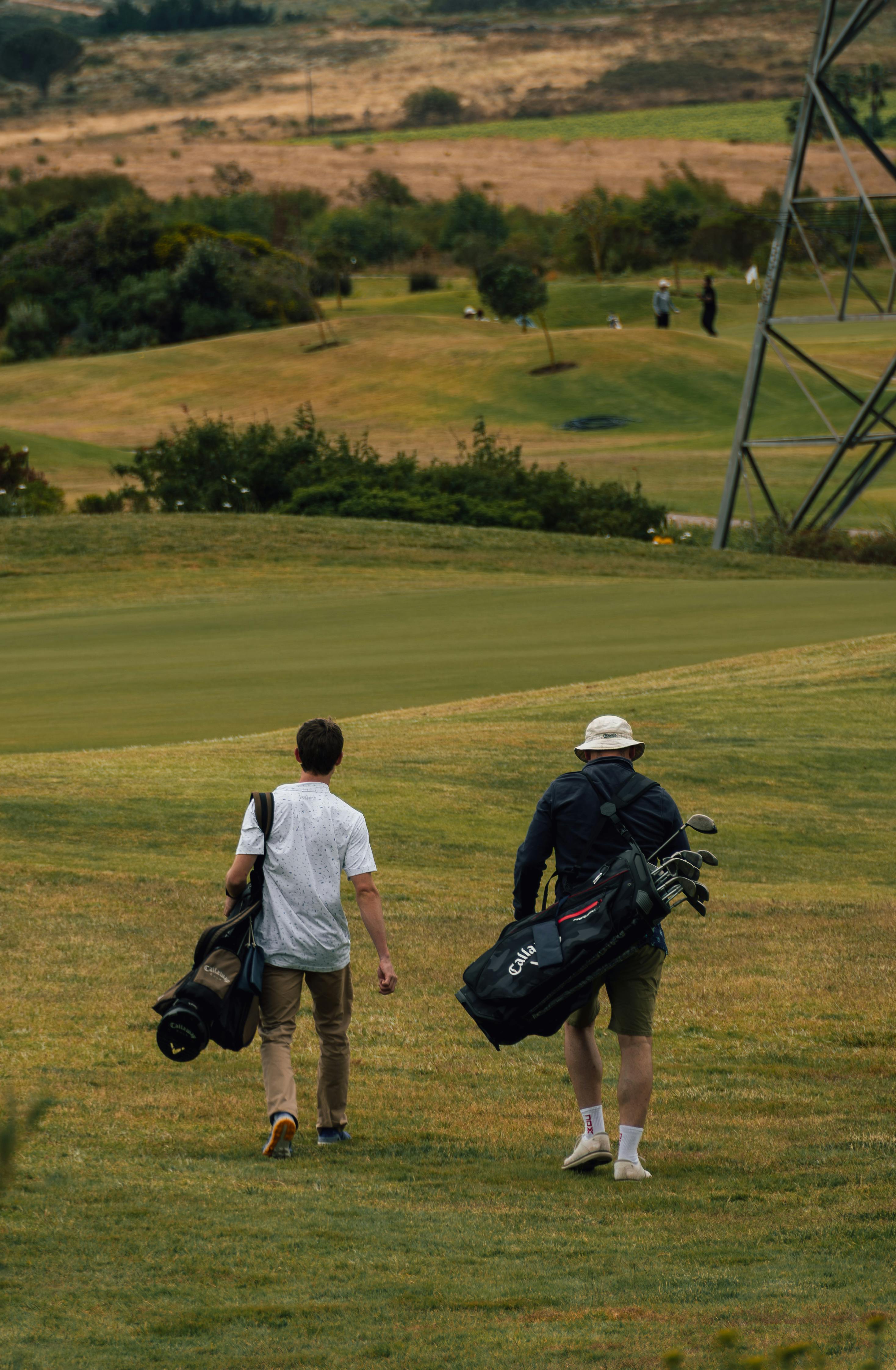 Golfers carrying bags on a scenic golf course in Cape Town, South Africa.