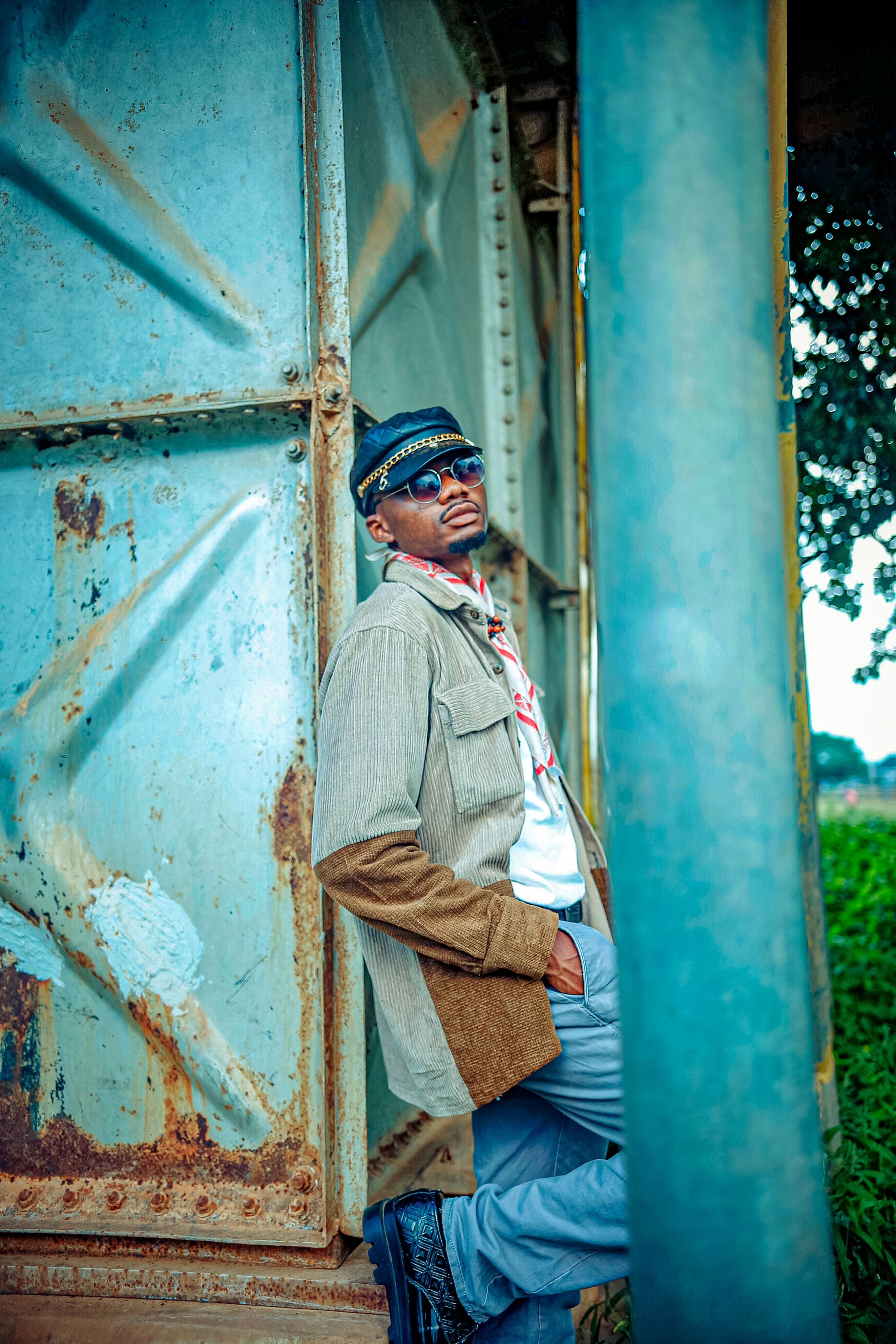 Fashionable male posing outdoors against a rusted metal backdrop, exuding urban style.