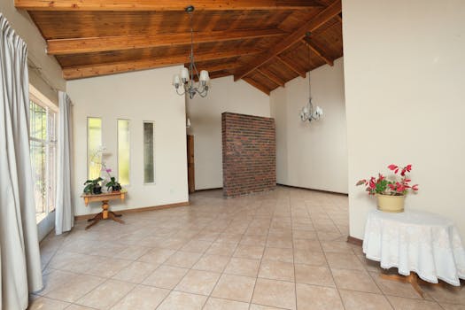 A bright and open modern room featuring wooden ceiling, brick accent wall, and elegant chandeliers.