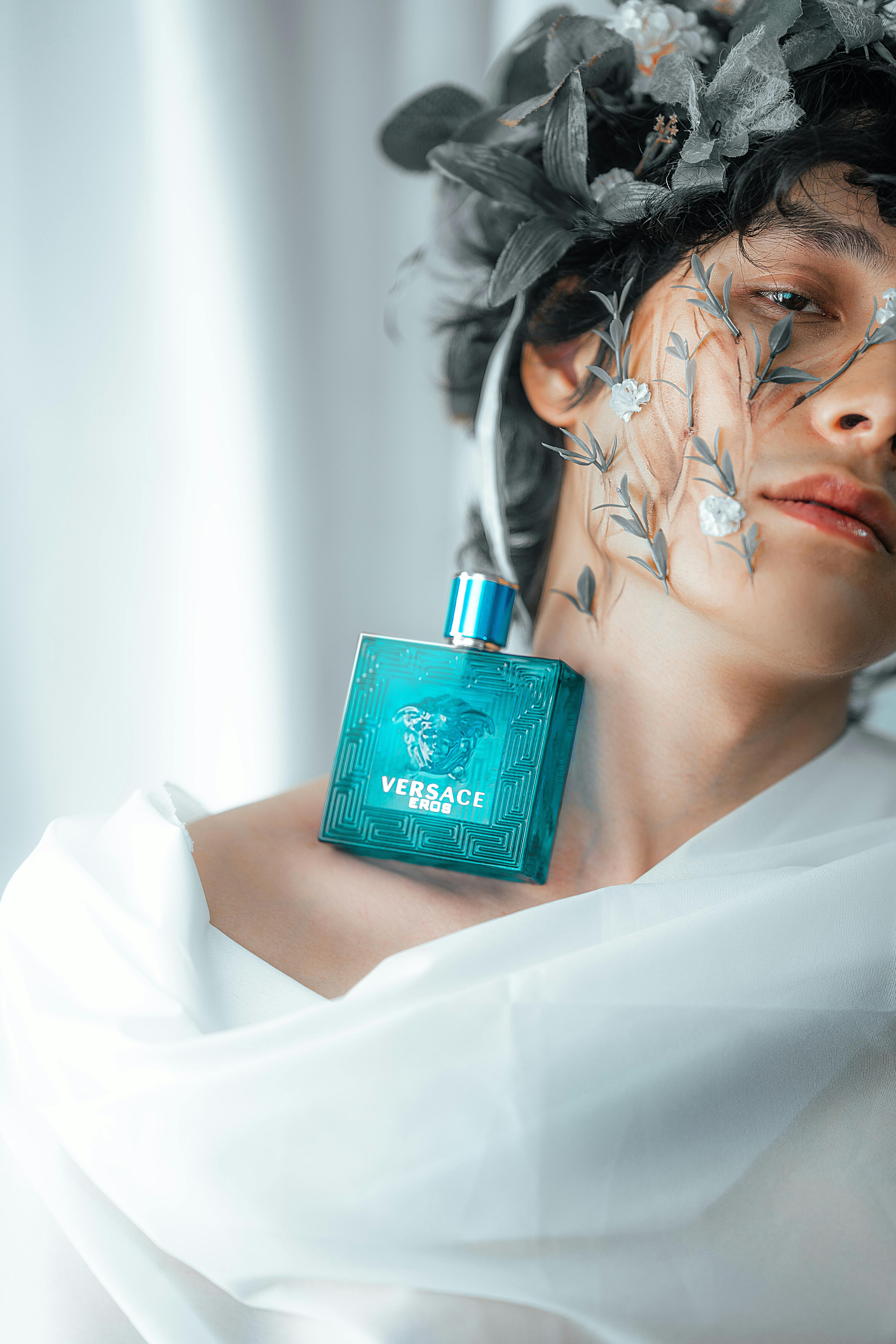 Artistic portrait featuring Versace perfume with floral headpiece and ethereal lighting.