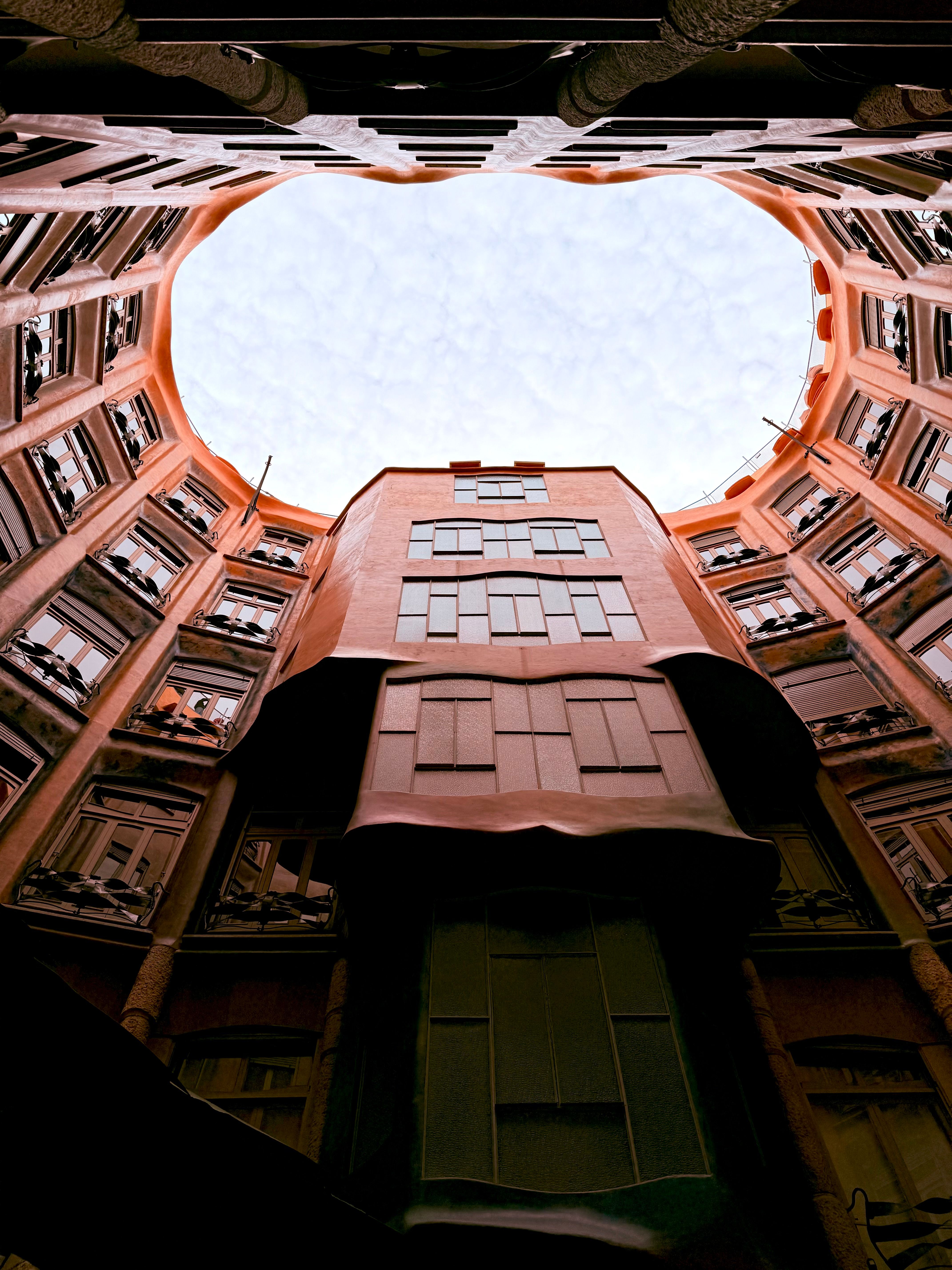 Looking up inside the iconic Casa Milà courtyard in Barcelona, showcasing its unique architecture.