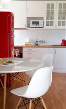 Bright kitchen with red fridge, white chairs, and elegant dining setup in modern design.
