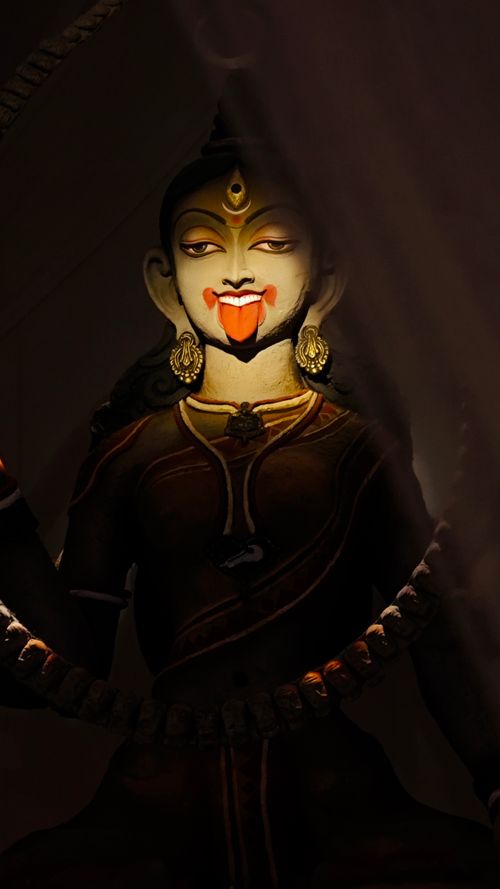 Free A captivating close-up of the Hindu goddess Kali statue, bathed in warm light and embraced by shadows. Stock Photo