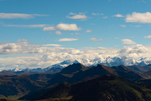 Stunning view of snow-capped mountains under a vibrant blue sky with clouds.