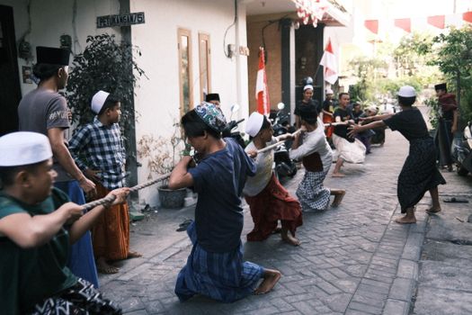 Group of men engaging in tug of war on a street in Indonesia, showcasing local culture.