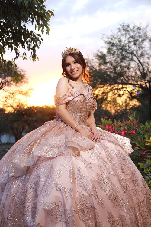 Free A young woman in a pink gown celebrates her quinceañera outdoors during a vibrant sunset. Stock Photo