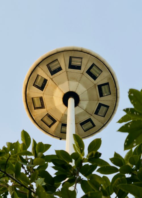 Free Observation tower resembling a UFO, viewed through lush foliage against a clear sky. Stock Photo