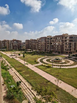 A scenic view of a modern apartment complex surrounded by lush greenery and clear blue skies.