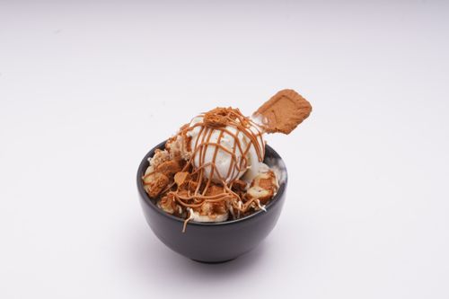 Free Black bowl with vanilla ice cream, biscuit, and caramel drizzle on a white background. Stock Photo