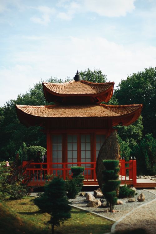 Free Tranquil Japanese garden featuring a traditional red pagoda surrounded by lush greenery. Stock Photo