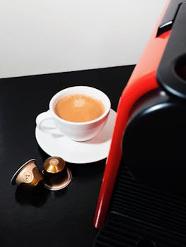 Delicious espresso served with coffee capsule pods beside a sleek coffee machine.