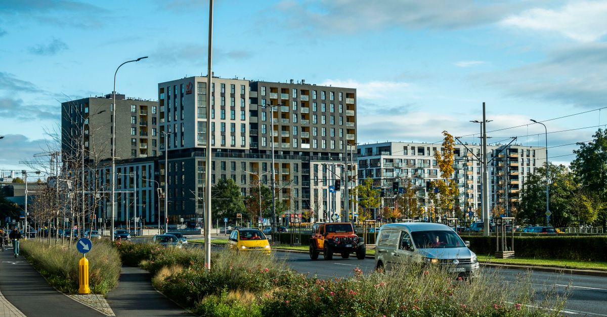 Vibrant cityscape featuring contemporary high-rise apartments, busy street, and lush greenery.