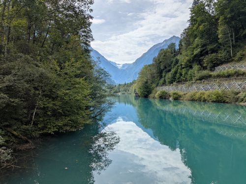 Free Breathtaking view of an alpine lake reflecting the mountains and lush greenery. Stock Photo