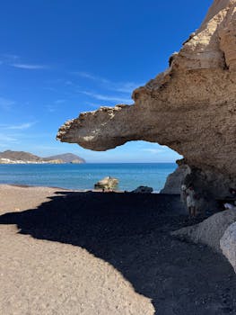 Natural rock arch by the sea with clear blue sky and ocean view.