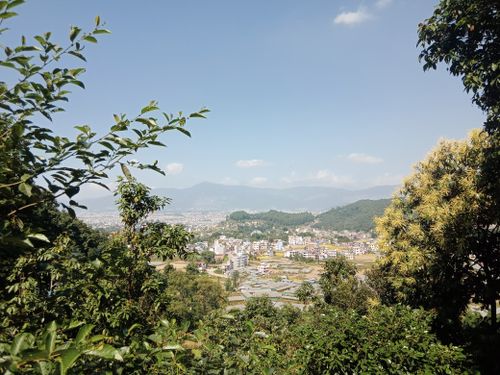 Free A panoramic view of a city surrounded by lush greenery and mountains. Stock Photo