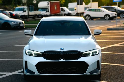 Free Front view of a sleek white car in a parking lot at sunset, showcasing luxury design. Stock Photo