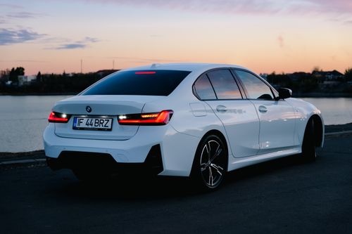 Free Elegant white sedan parked by the river during a vibrant sunset. Stock Photo