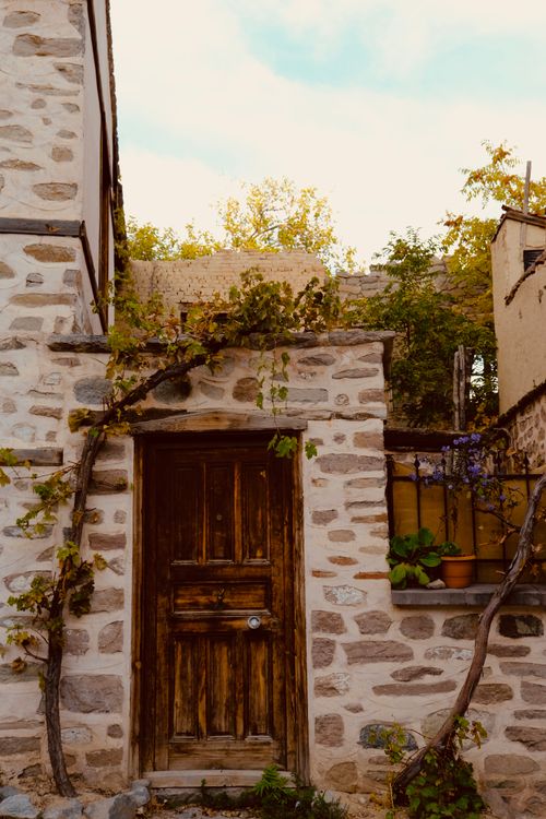 Free Charming rustic stone house entrance with wooden door and autumn foliage Stock Photo