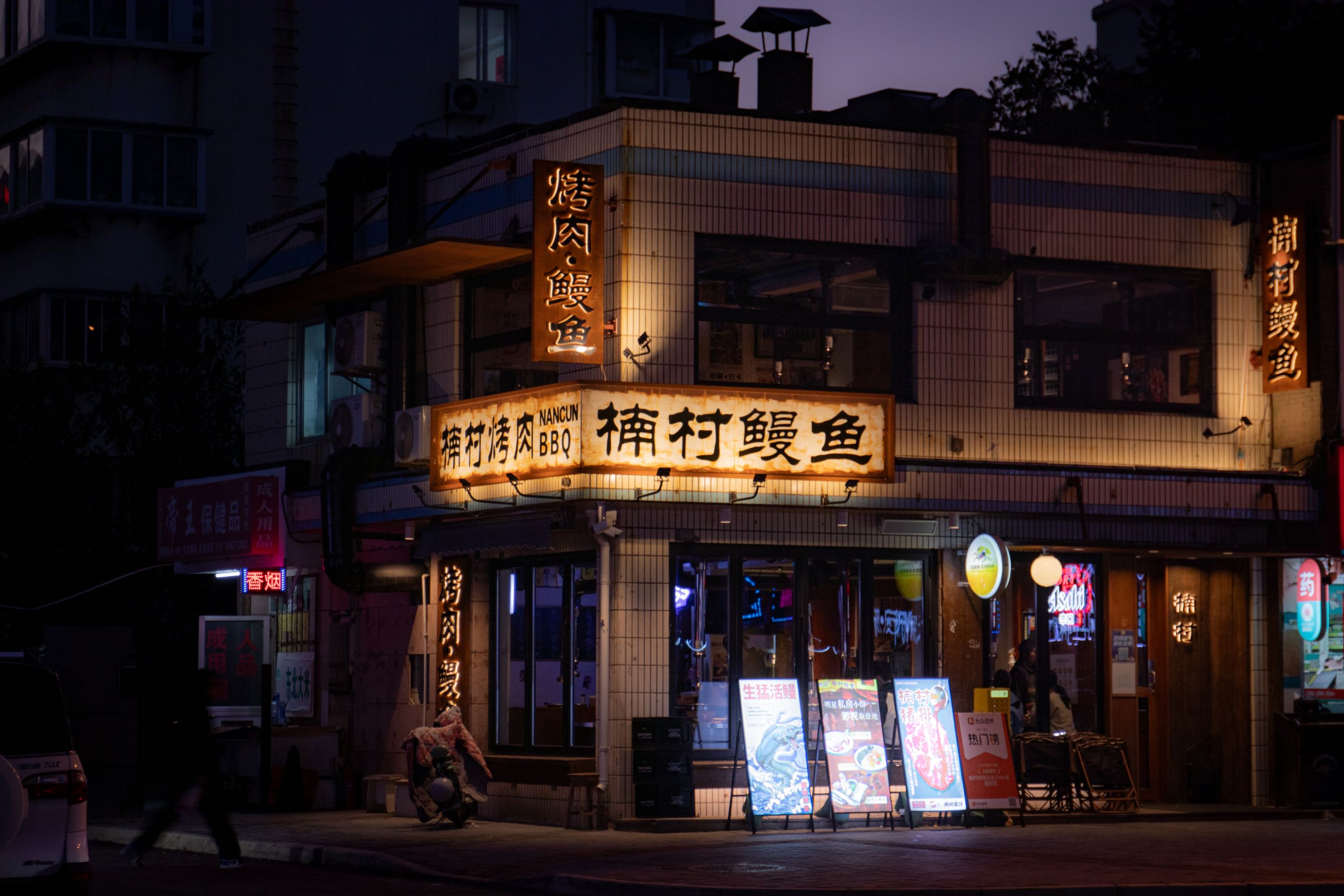 Illuminated restaurant signage on a street corner at night