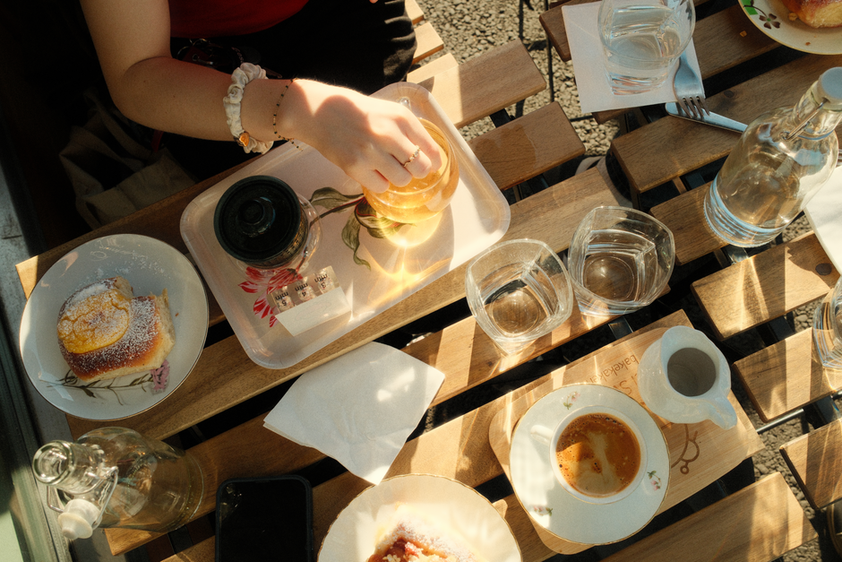 Charming breakfast scene with coffee and pastry on wooden table, enhanced by morning sunlight.