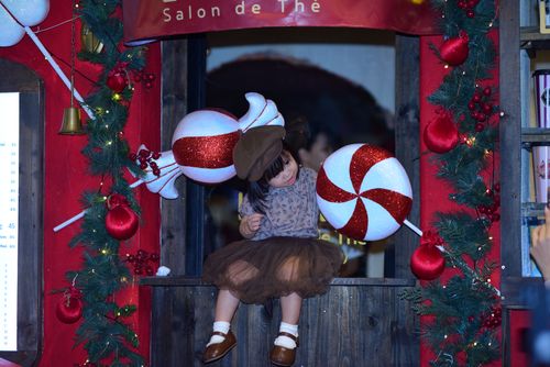 Free A child sits in a window adorned with Christmas-themed decorations. Stock Photo