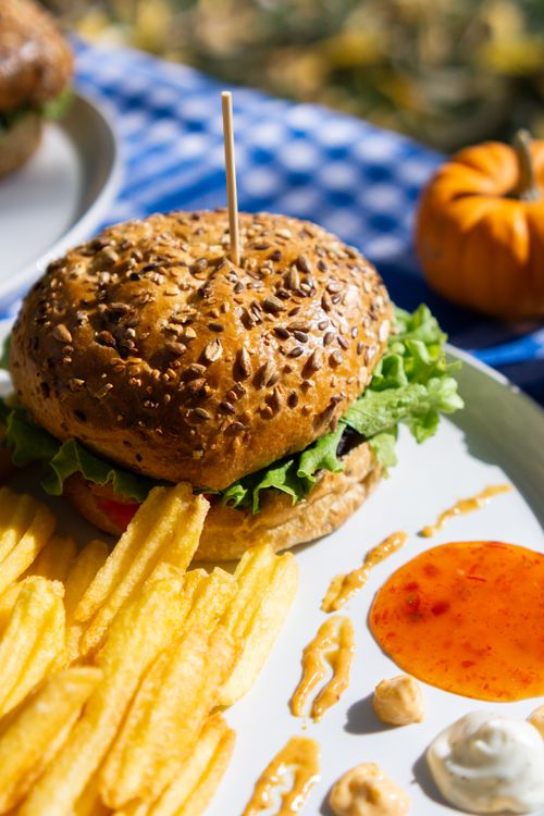 Free Appetizing burger with fries on a picnic table, perfect for outdoor dining enthusiasts. Stock Photo