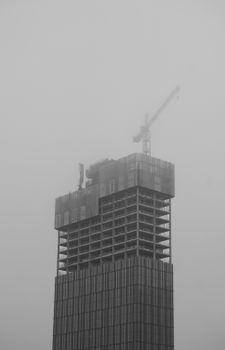 A foggy scene of a high-rise construction with crane, black and white, Manchester skyline.