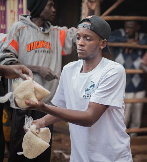 Free Young volunteers distribute food packs to community members during a charity event. Stock Photo