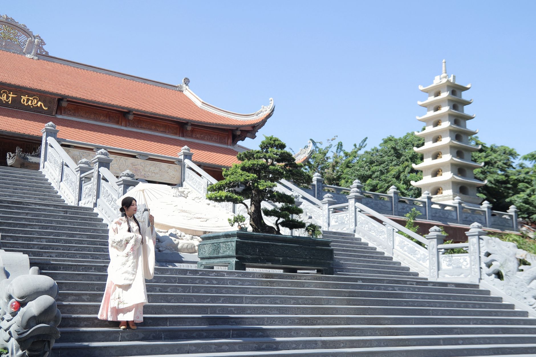 Woman in traditional Hanfu outfit ascending temple steps surrounded by serene architecture.