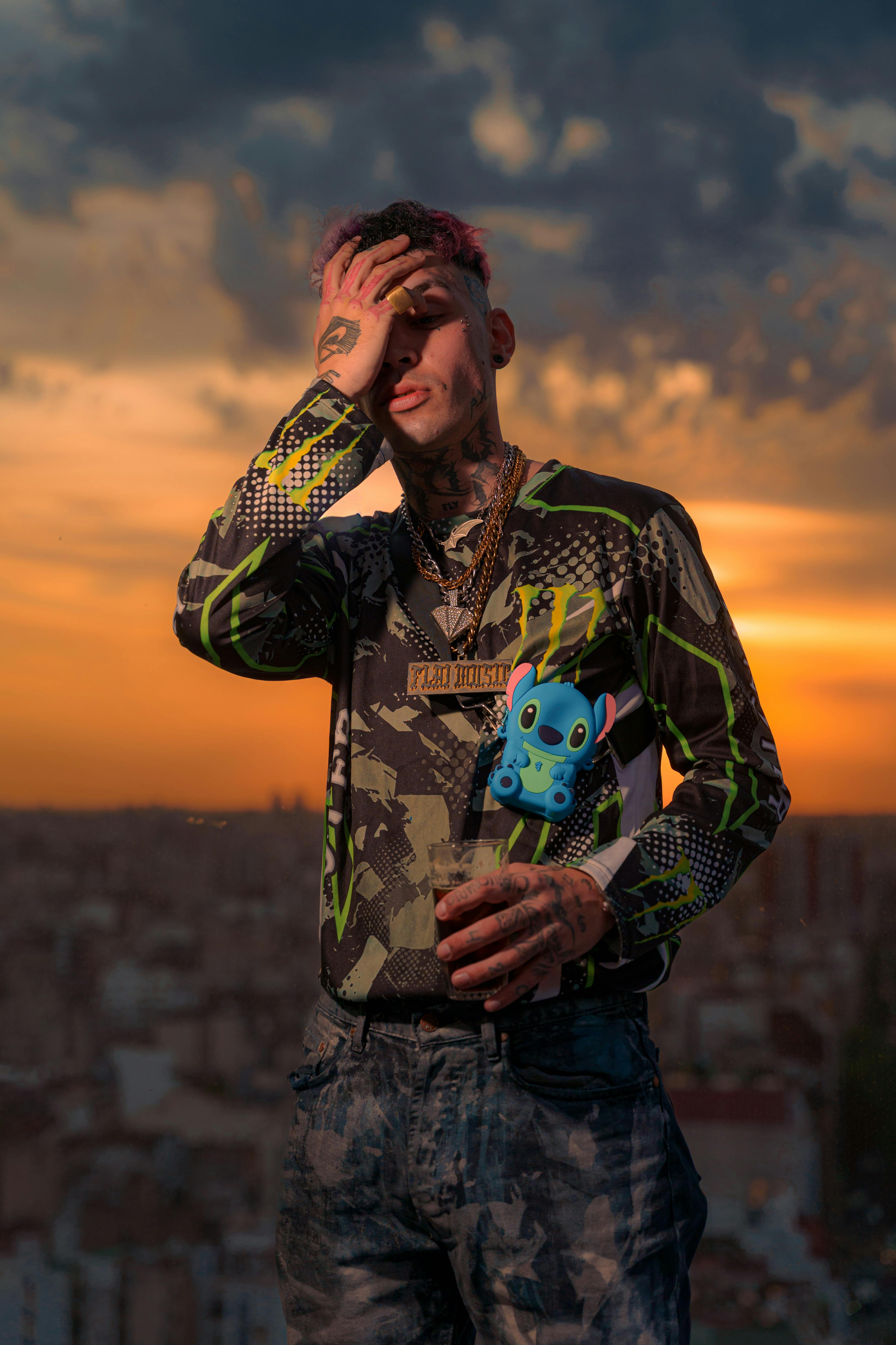 Man posing with colorful shirt and toy accessory against sunset urban backdrop.