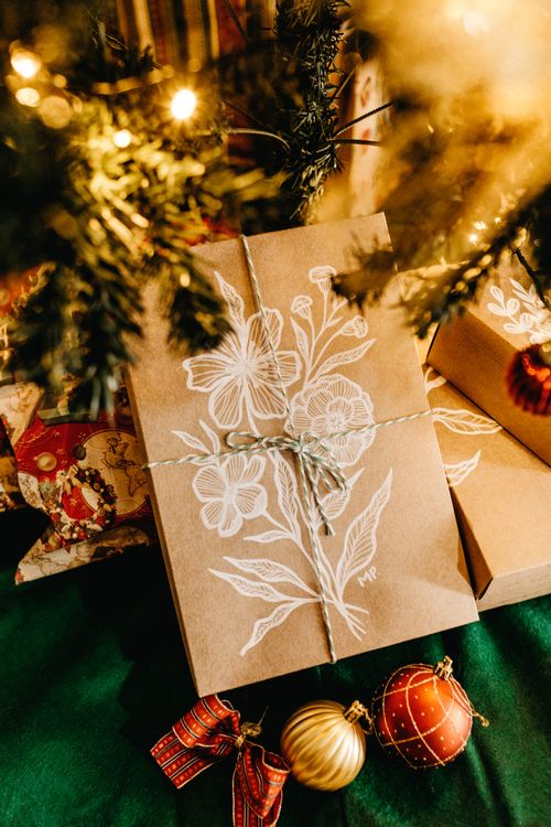 Free Rustic gift boxes with floral designs under a decorated Christmas tree, showcasing festive holiday spirit. Stock Photo