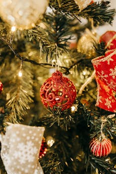 充满活力的红色装饰品挂在节日圣诞树上，金色的灯光和丝带点缀其间，唤起节日的欢呼