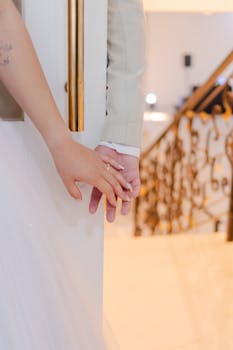 Bride and groom holding hands behind a door, symbolizing love and union.