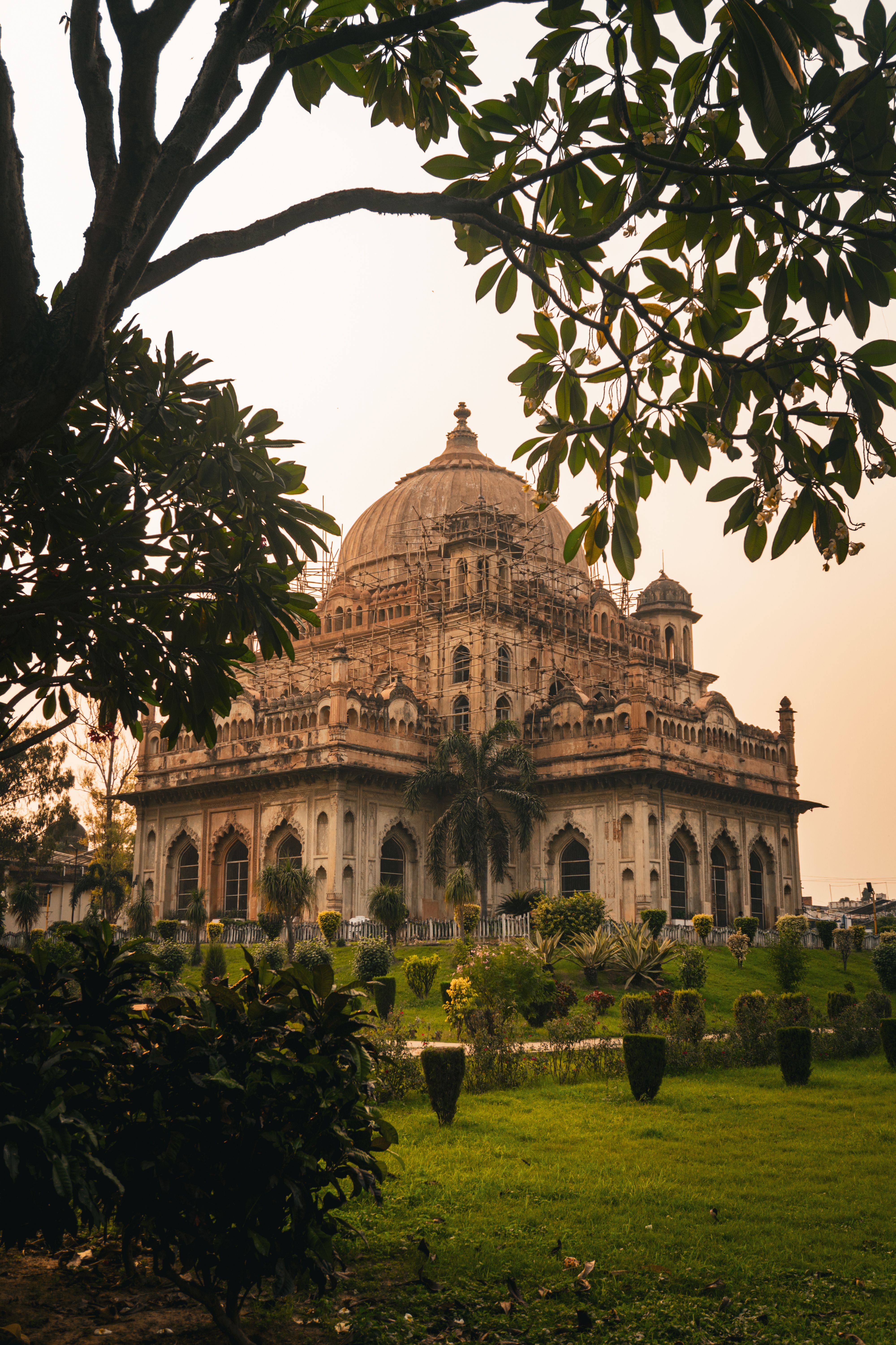 Explore a stunning historical tomb in Lucknow, surrounded by vibrant gardens under a warm sky.