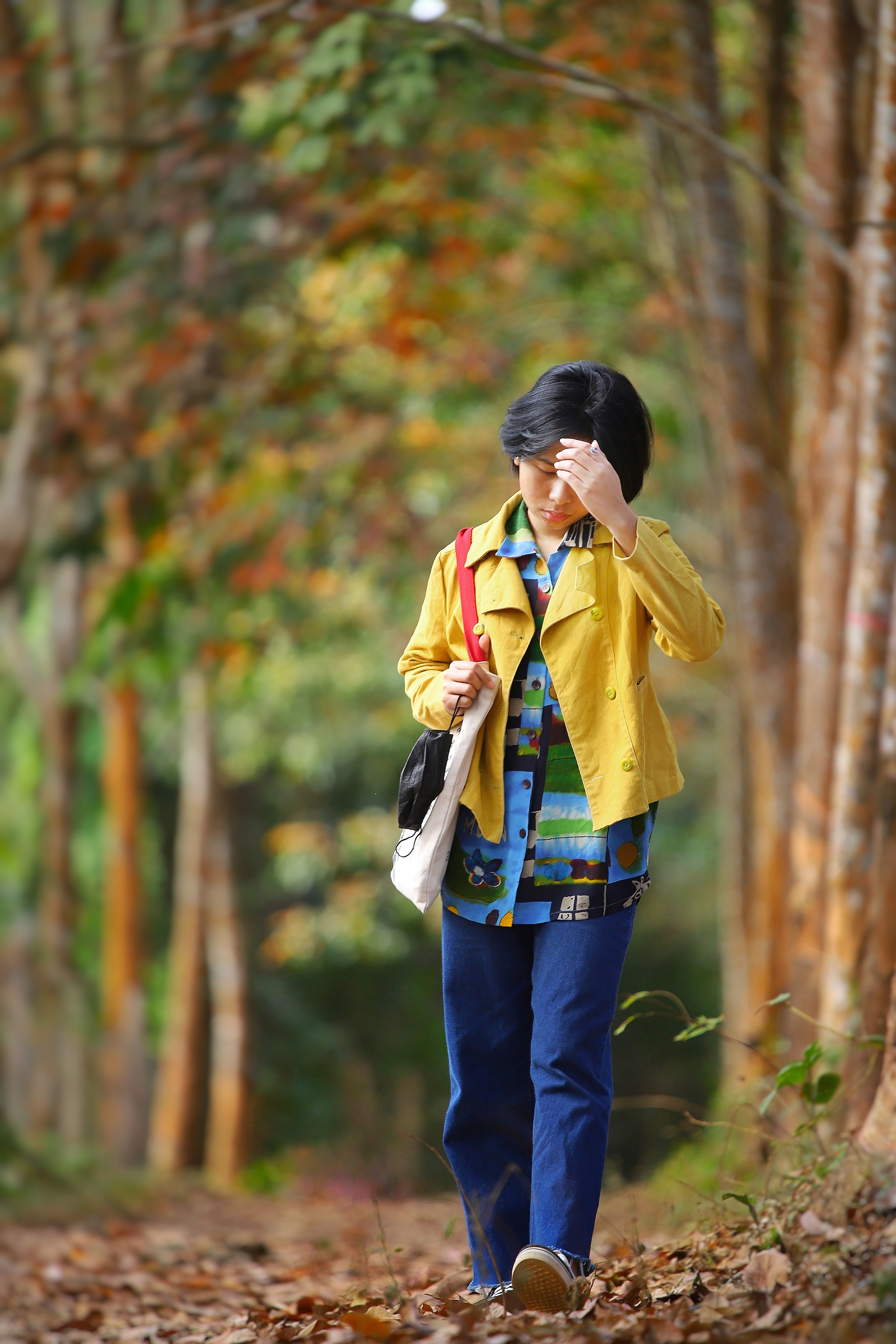 A woman strolling through a scenic forest path surrounded by autumn foliage, capturing the essence of fall.