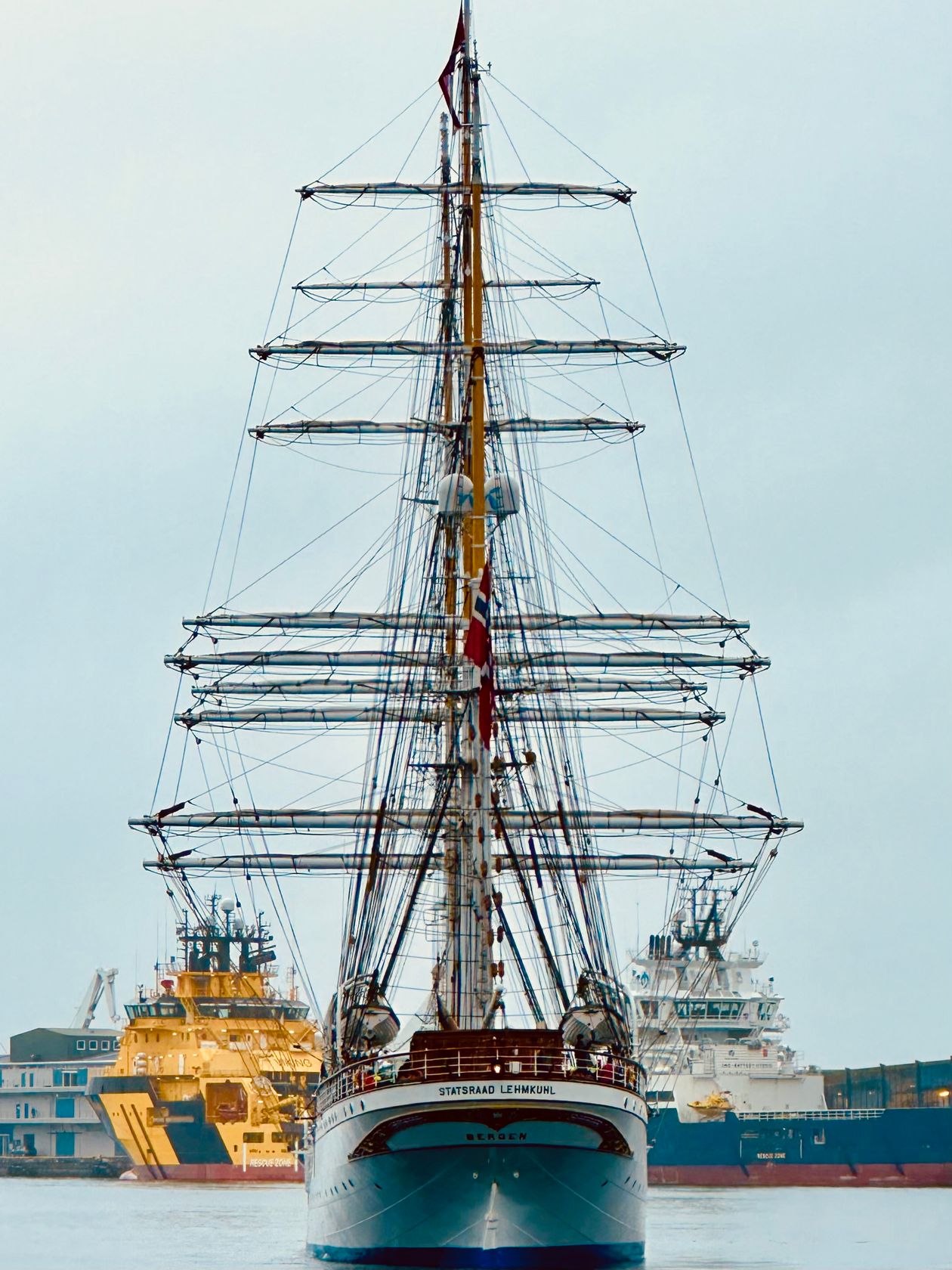 Tall ship with towering masts moored in a busy harbour, evoking the Belem alongside other vessels at the Armada de Rouen