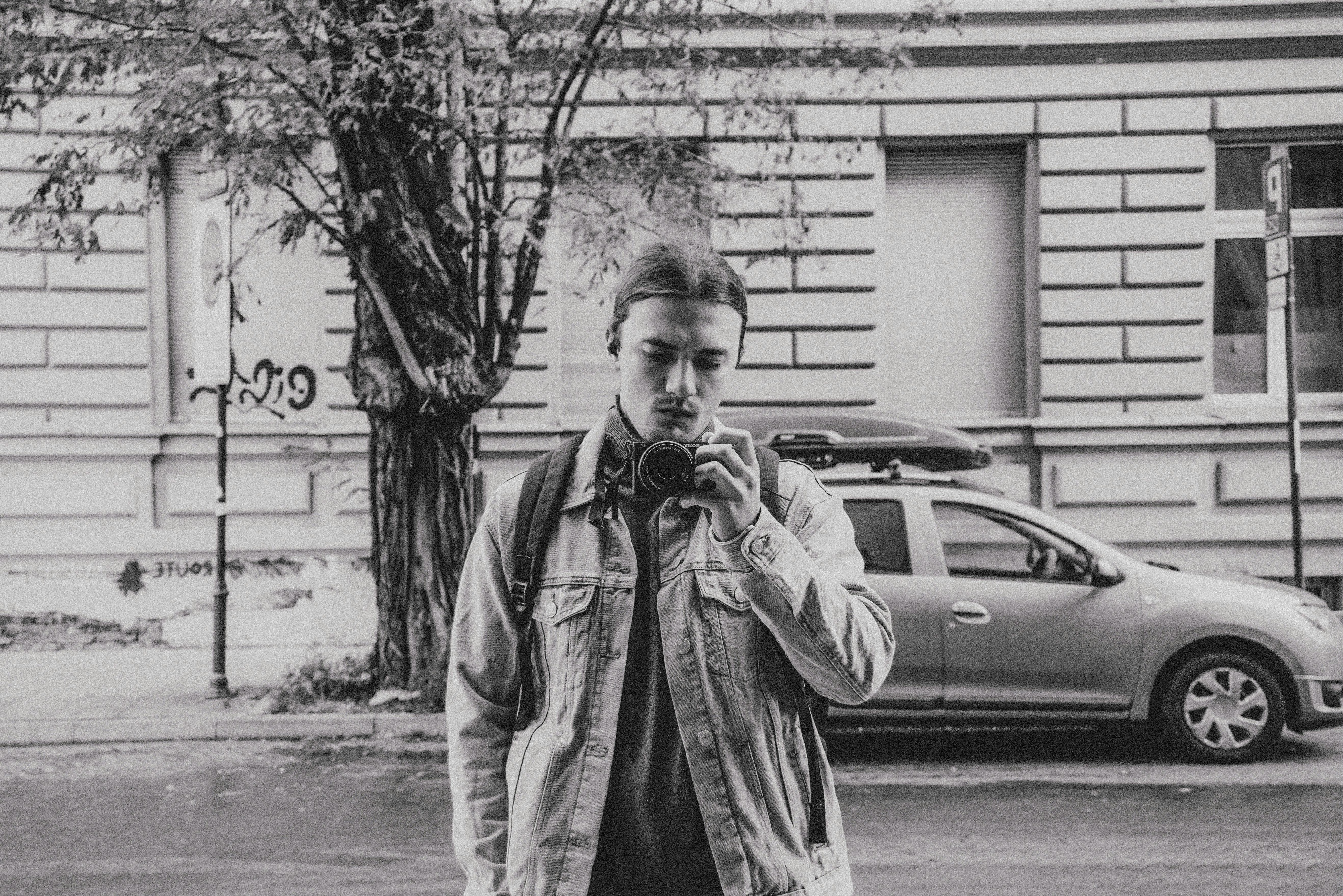 Gratis Monokrom gateportrett av en ung mann med kamera i Łódź, Polen. Arkivbilde