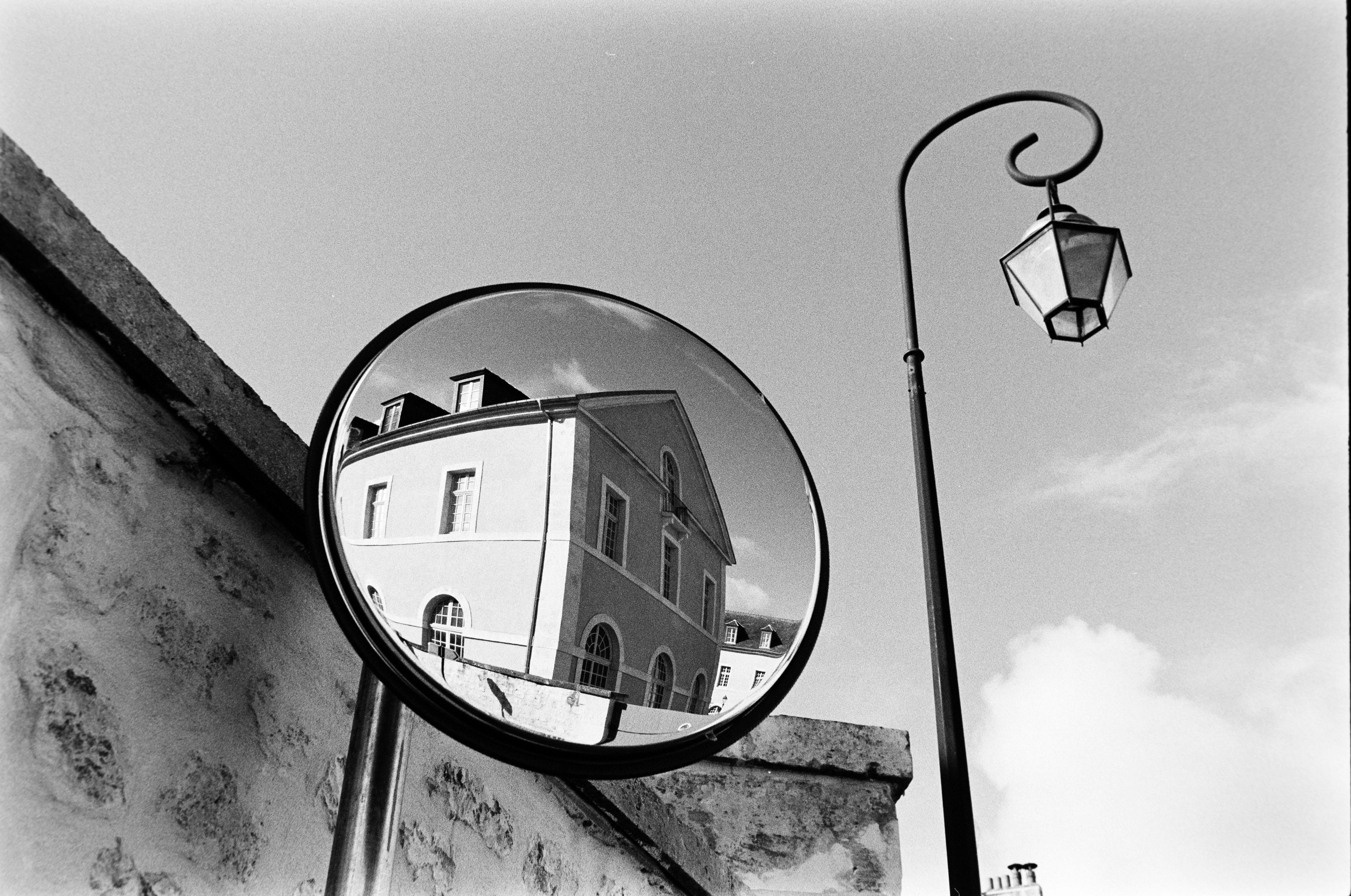 Black and white photo of a building reflection in a street mirror in Compiègne, France.