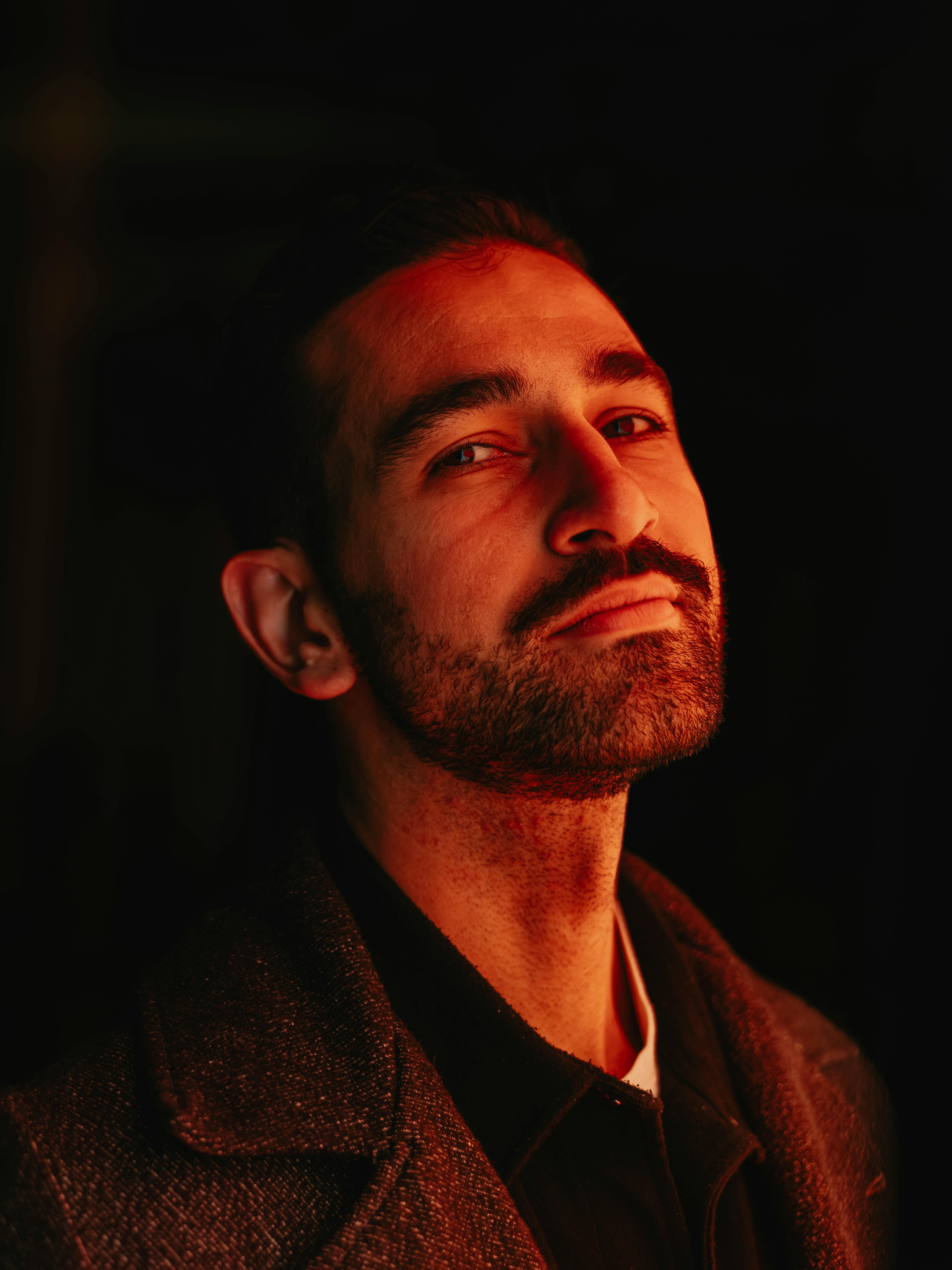 A dramatic portrait of an adult male with moody lighting, showcasing artistic expression and depth.