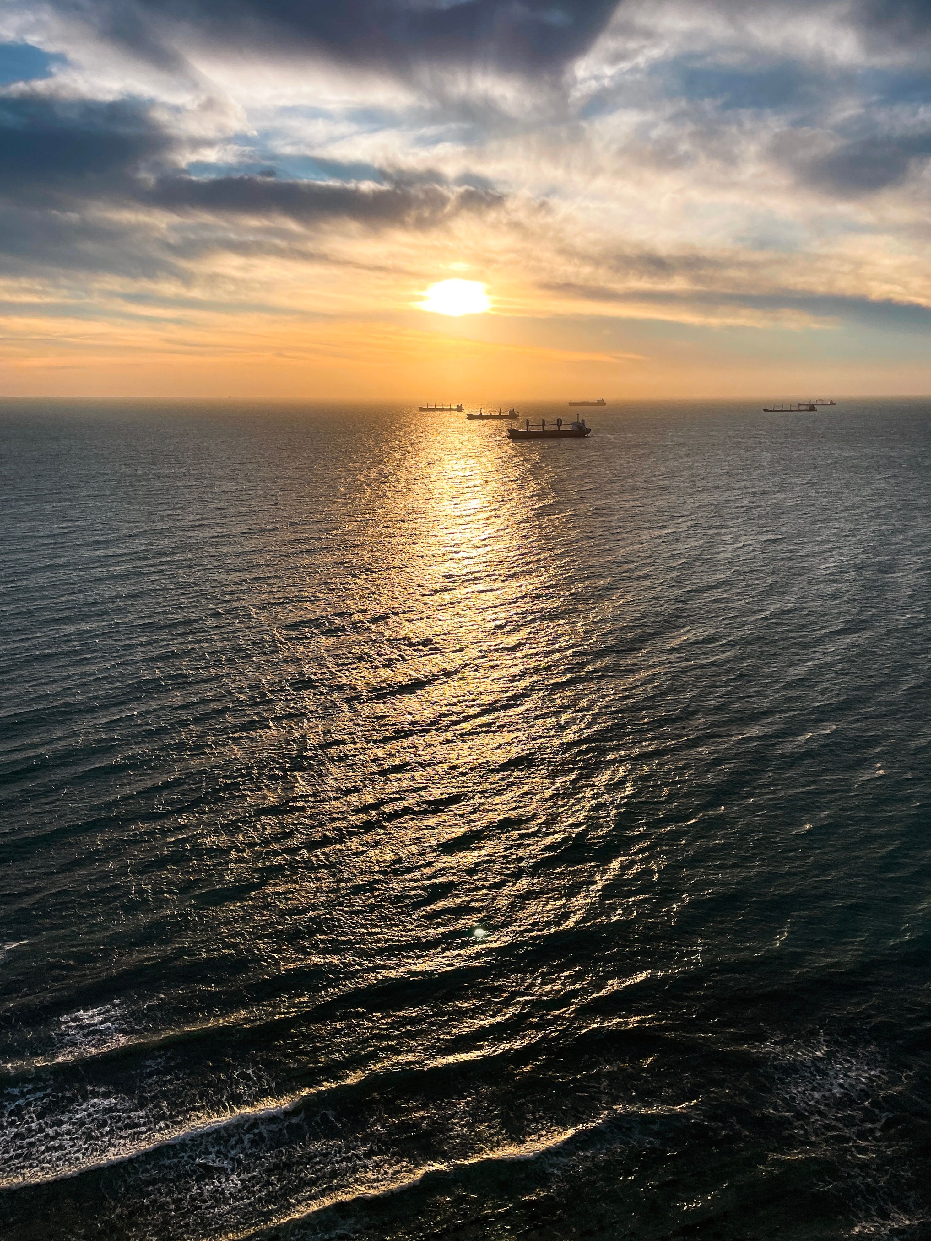 Stunning Sunset Over Calm Ocean with Silhouetted Ships · Free Stock Photo