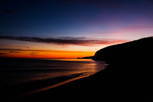 Scenic beach sunset in İstanbul with vibrant hues of orange and blue over the calm ocean.