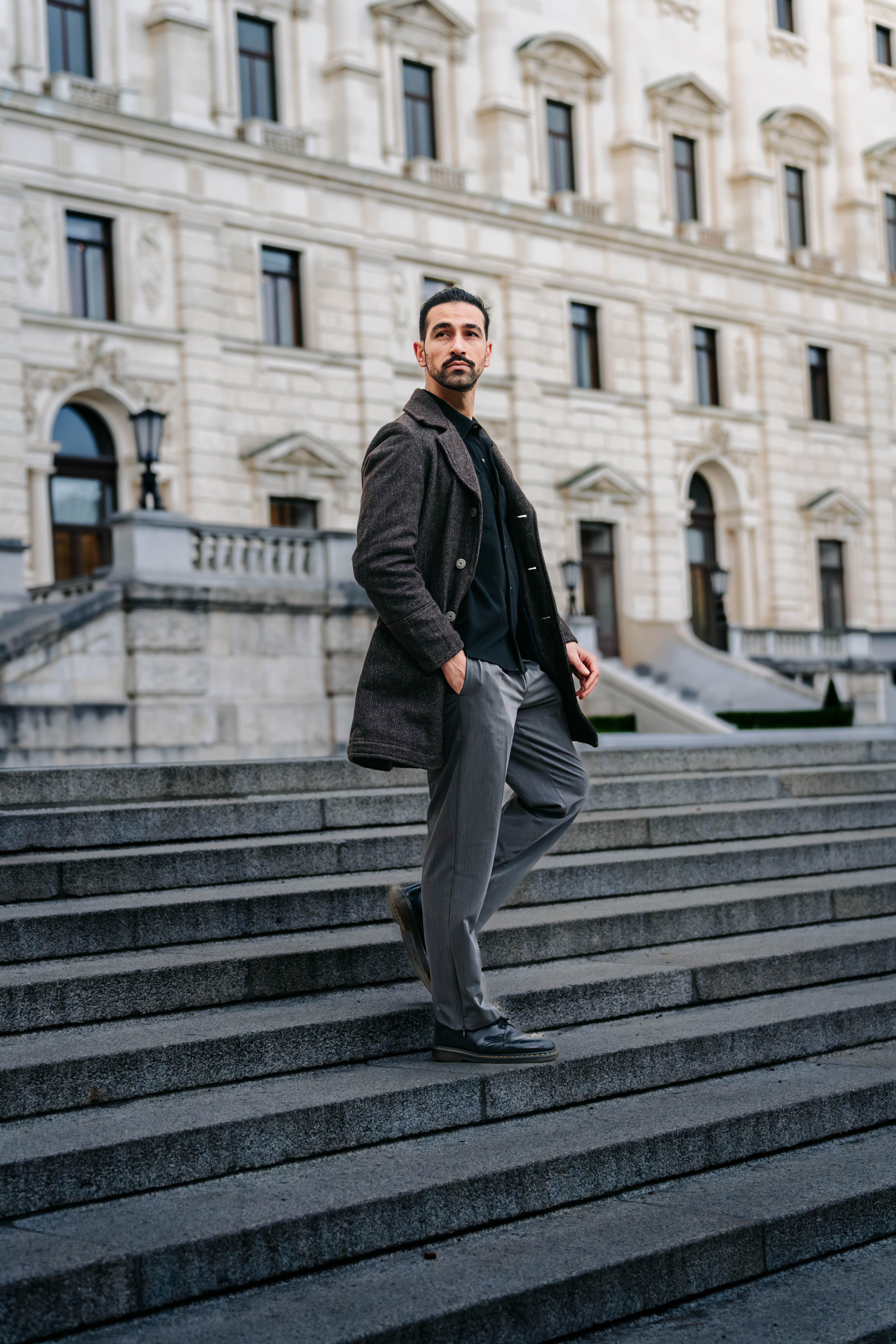 Portrait of a stylish man on steps in Vienna, capturing classic European architecture.