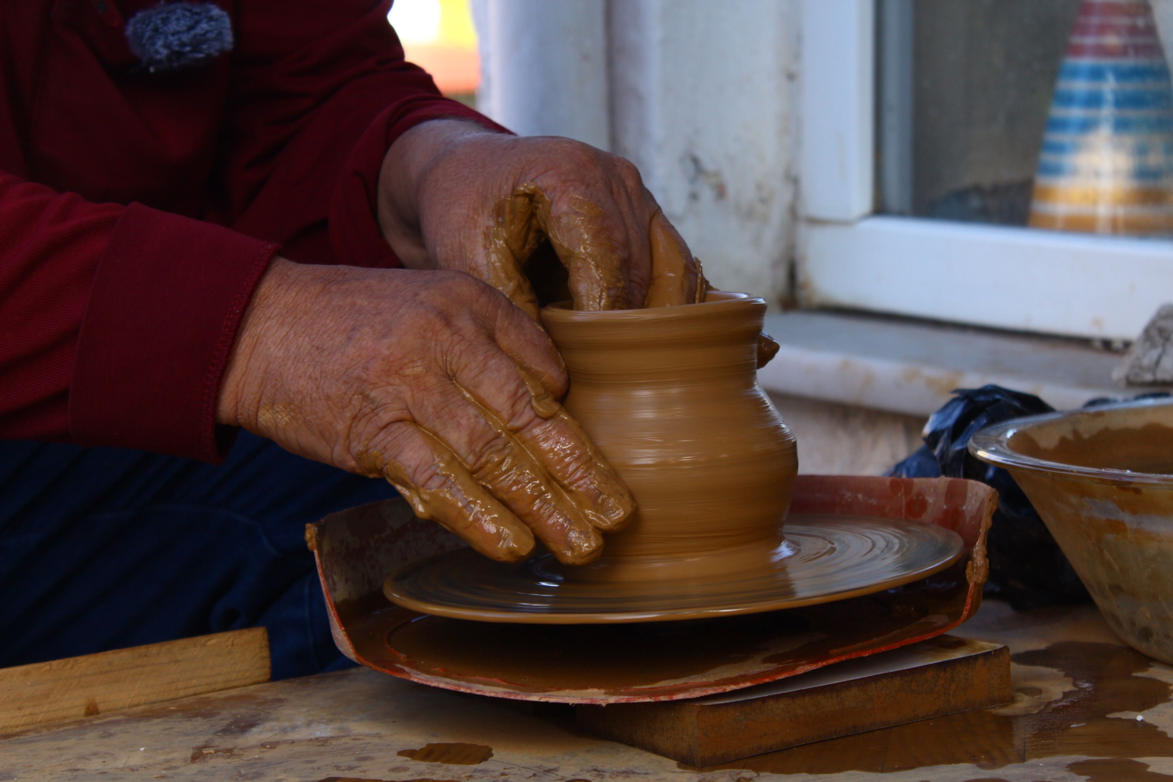 close-up of hands making pottery in a small village, no faces visible, warm lighting