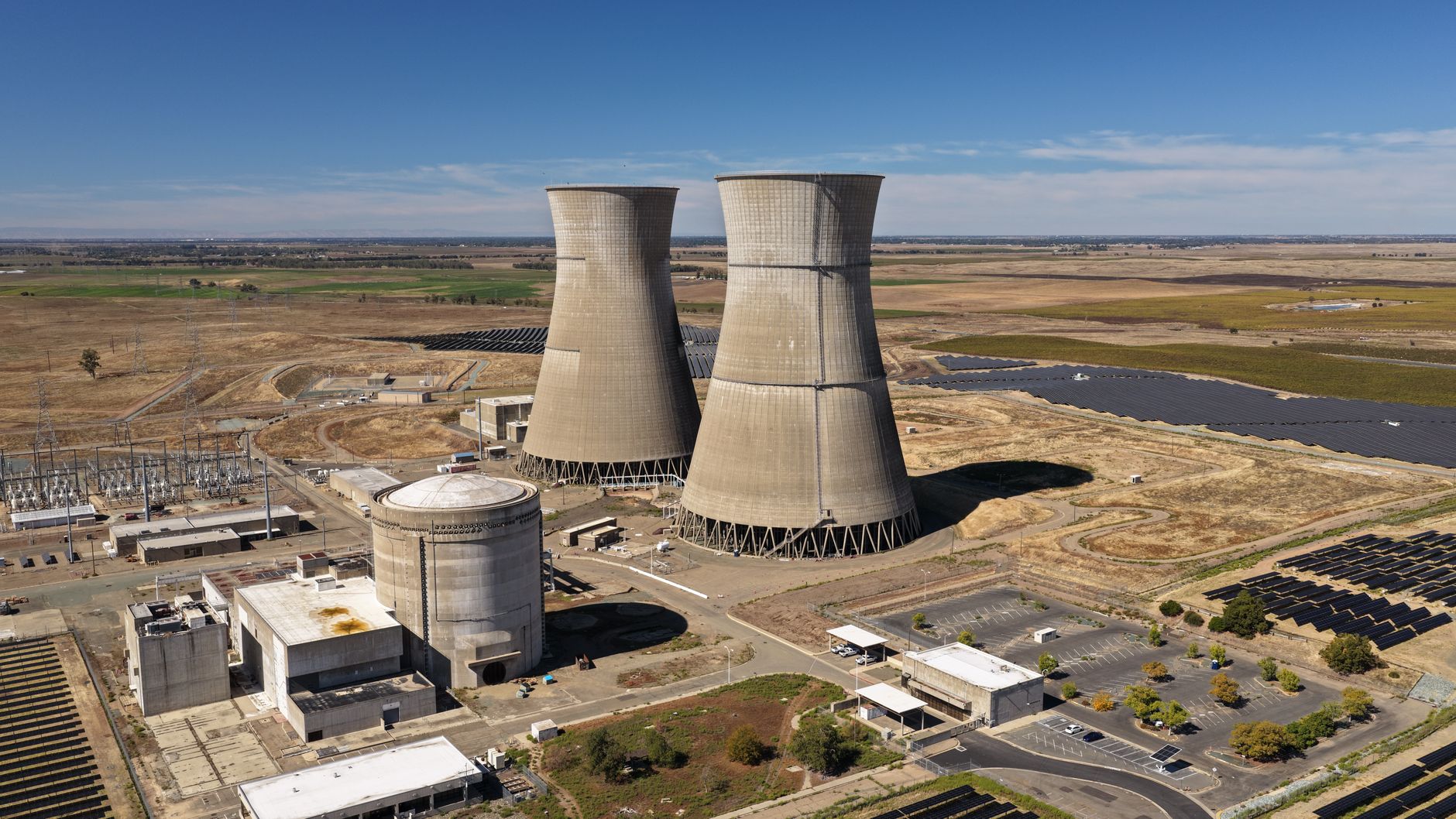 Aerial view of large cooling towers at a power plant on a sunny day.