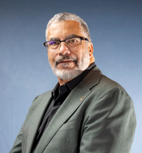 Free Portrait of a mature man with glasses and beard in a formal green suit against blue background. Stock Photo