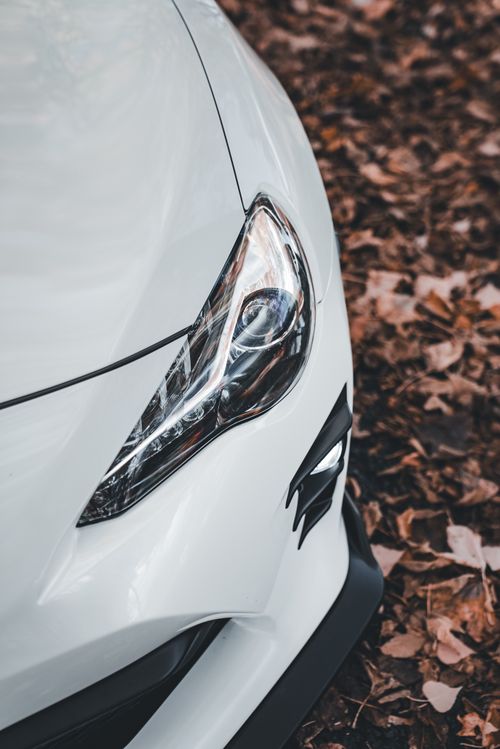Free A stylish car's headlight captured against a backdrop of dry autumn leaves, highlighting elegance and design. Stock Photo