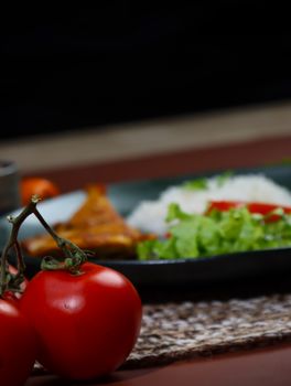Close-up of fresh tomatoes with a gourmet dish in the background featuring rice and vegetables.