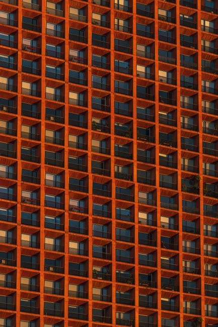 Vivid orange architectural facade showcasing geometric balcony patterns in Mexico City at sunset.