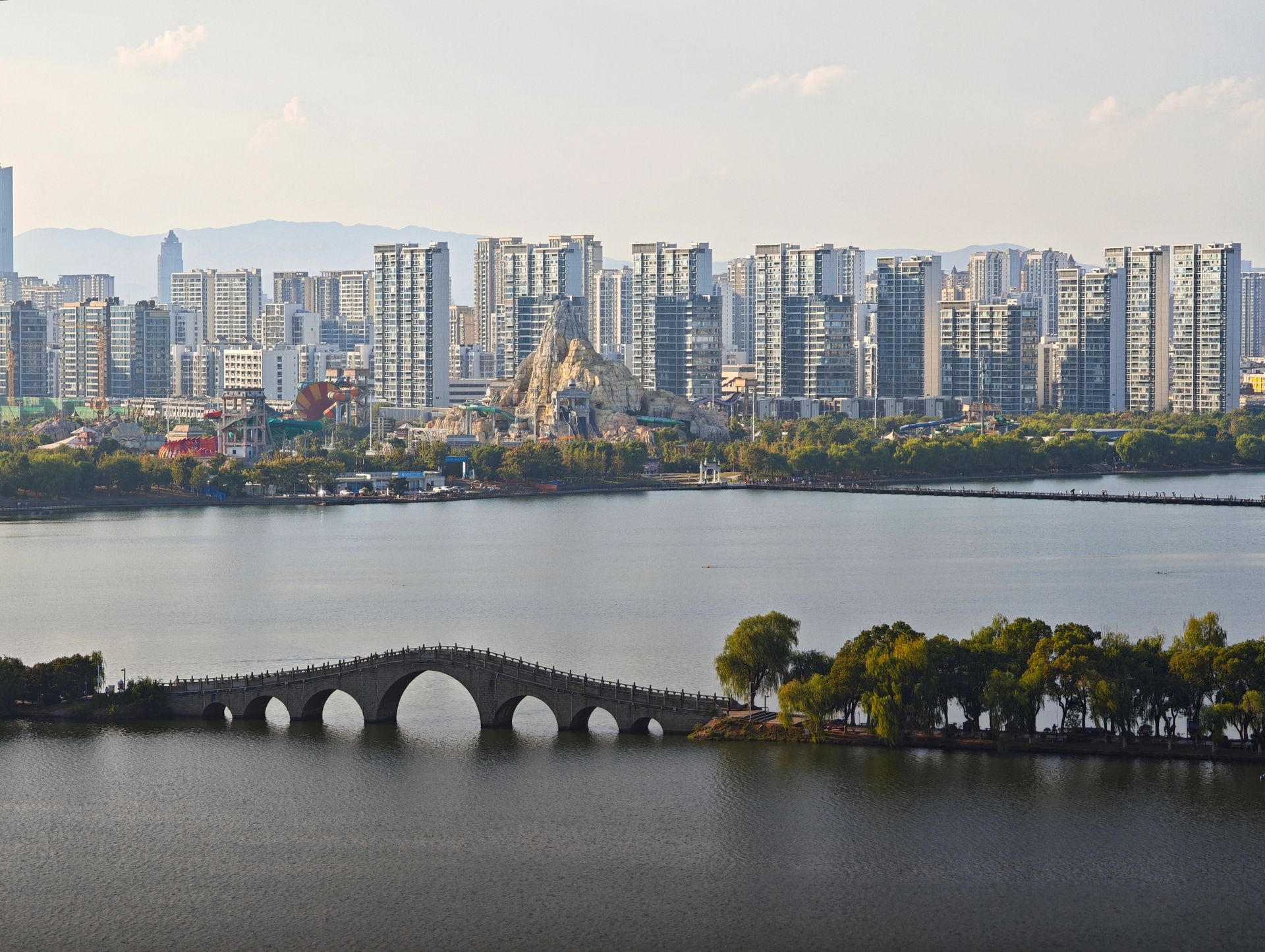 A beautiful urban skyline with a traditional bridge spanning across a lake.